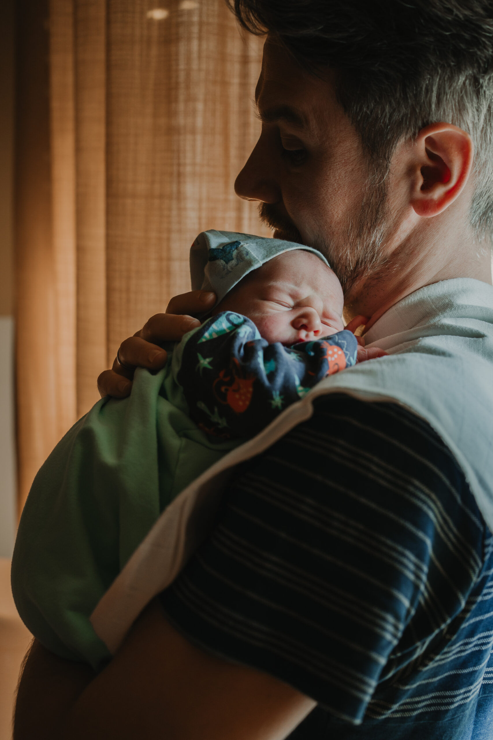 Papa hält sein Neugeborenes im Arm. Dokumentarische Familienfotografie Graz.