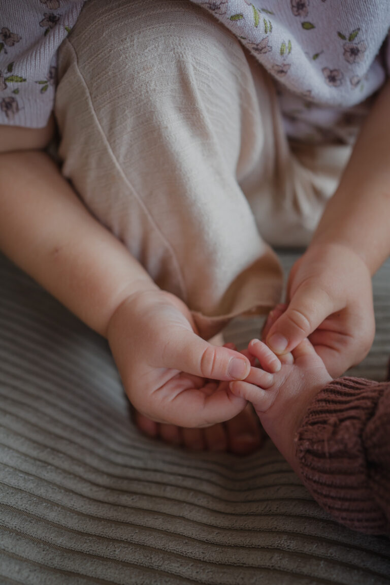 Große Schwester hält die Babyfüße – natürliche Familienfotos Graz und Umgebung, authentische Geschwistermomente