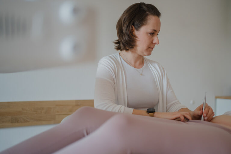 Physiotherapeutin behandelt Patientin – Businessfotografie Graz und Umgebung, authentische Arbeitsmomente in der Praxis