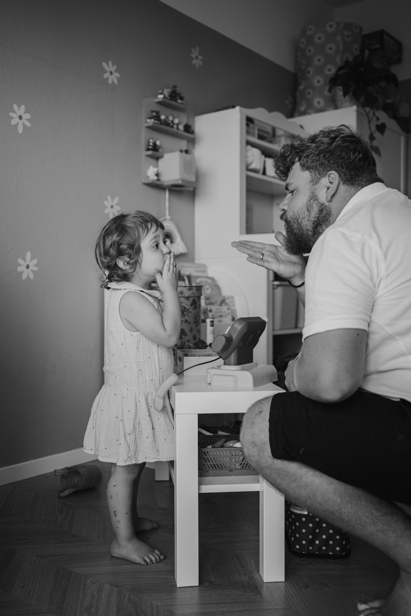 Papa und Tochter werfen sich einen Luftkuss zu – natürliche Familienfotos Graz und Umgebung