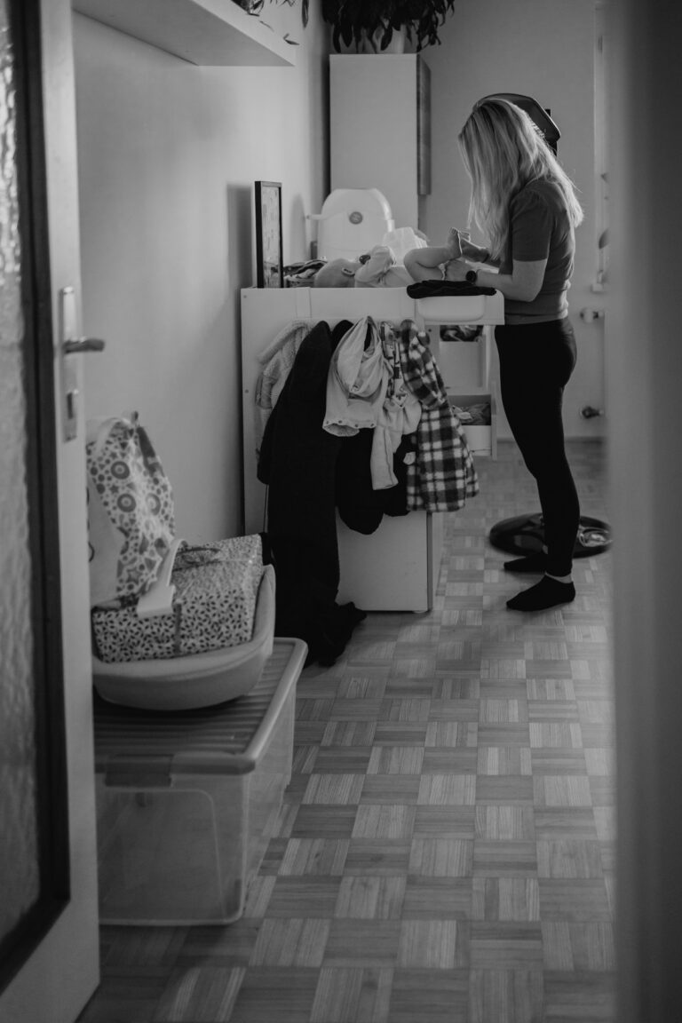 Mama steht am Wickeltisch und wechselt Windel. angestellte fotografie Graz