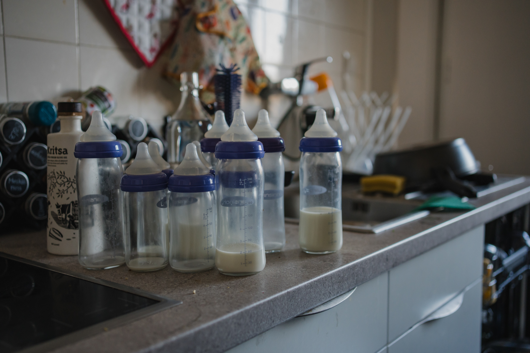 einige halmvolle Babyflaschen stehen in der Küche. authentische Newbornfotografie Graz