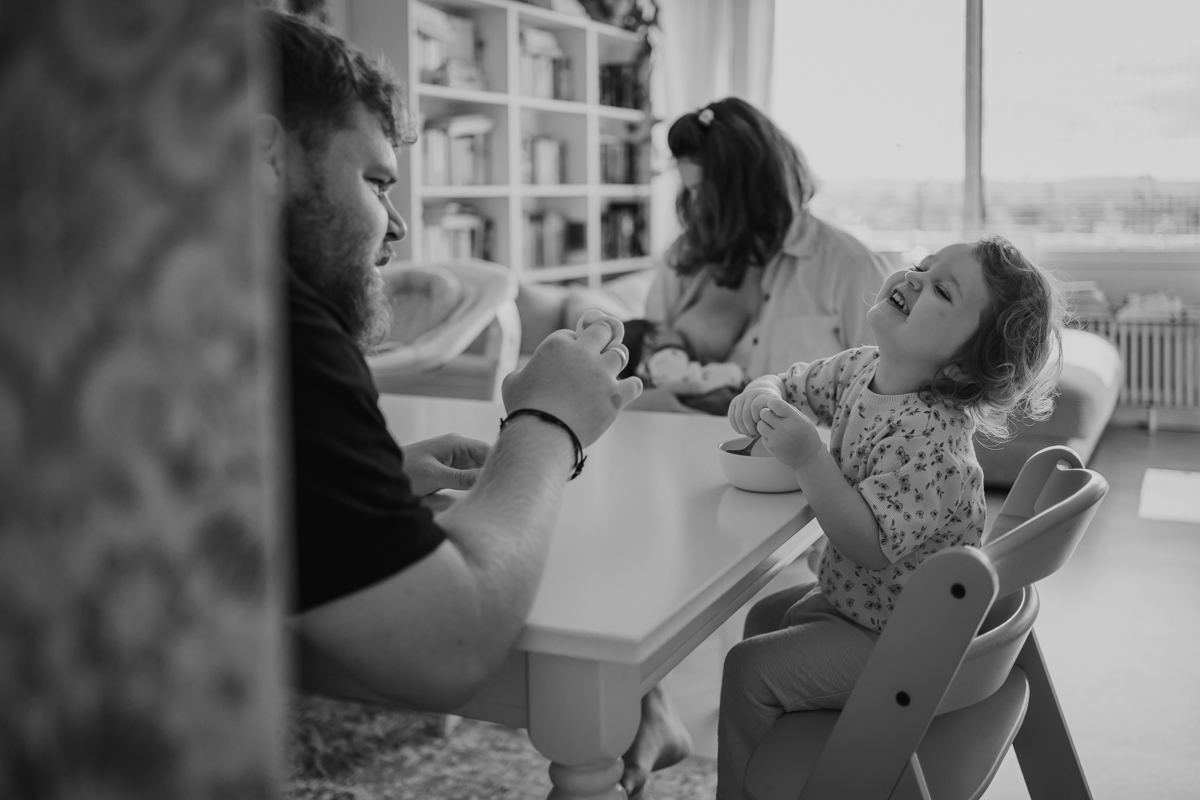 Familie lacht gemeinsam am Tisch – natürliche Familienfotos Graz und Umgebung, authentische Alltagsszenen