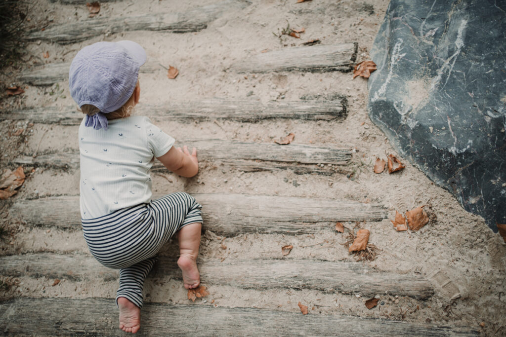 Kind krabbelt über den Sand – natürliche Familienfotos Graz und Umgebung, authentische Alltagsszenen