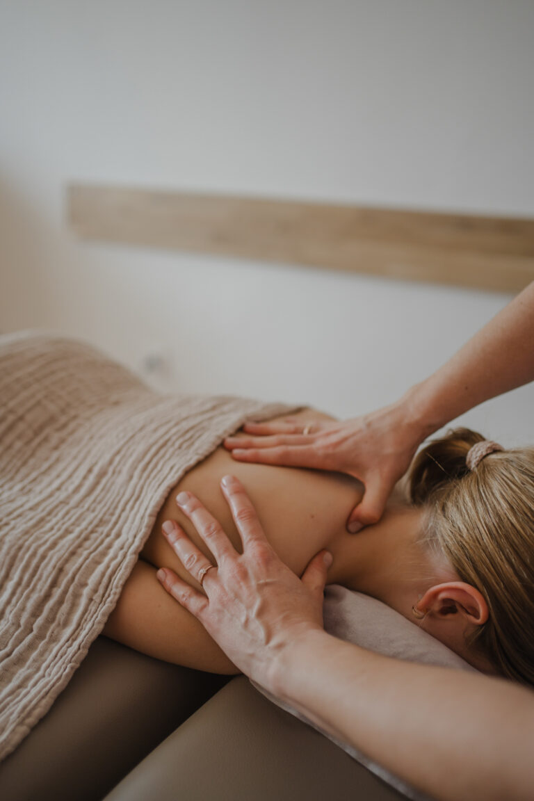 Physiotherapeutin massiert Patientin – Businessfotografie Graz und Umgebung, authentische Arbeitsmomente in der Praxis