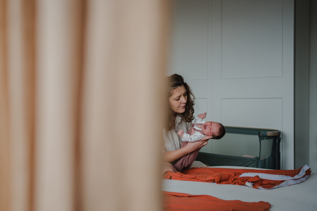 Mama nimmt ihr Neugeborenes hoch – dokumentarische Newborn- und Familienfotografie Graz und Umgebung, natürliche Alltagsmomente