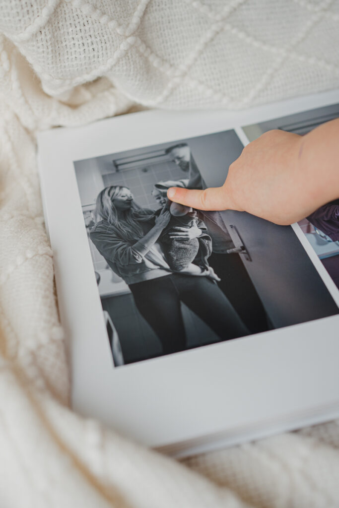 Kind hält ein Fotobuch mit dokumentarischer Familienfotografie aus Graz und betrachtet aufmerksam die Bilder