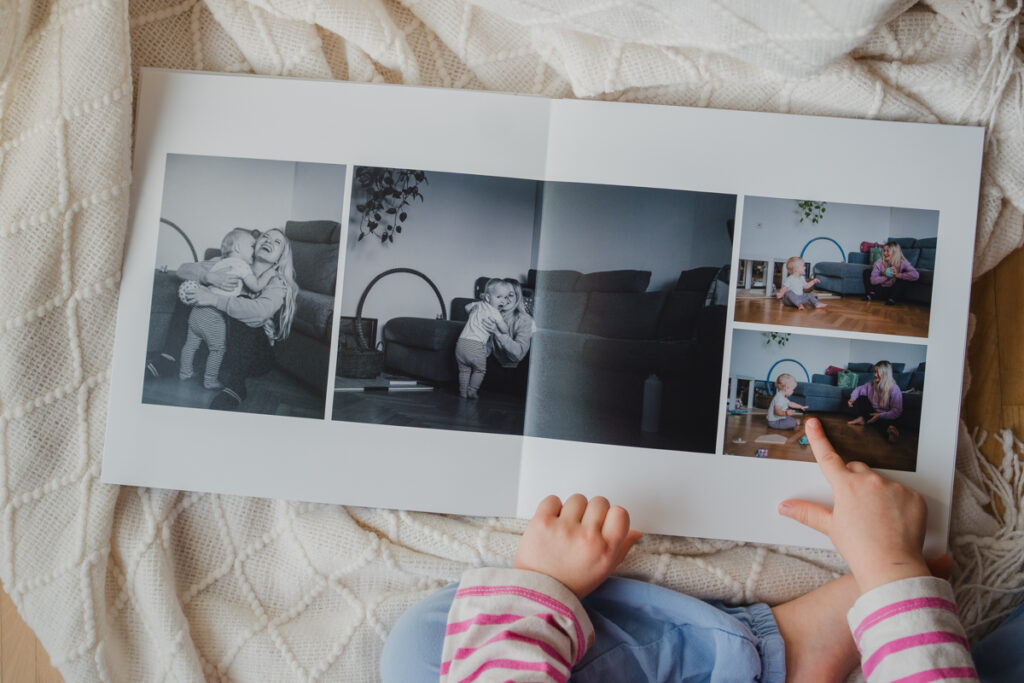 Kind blättert konzentriert in einem Fotobuch mit authentischer Familienfotografie aus Graz und Umgebung