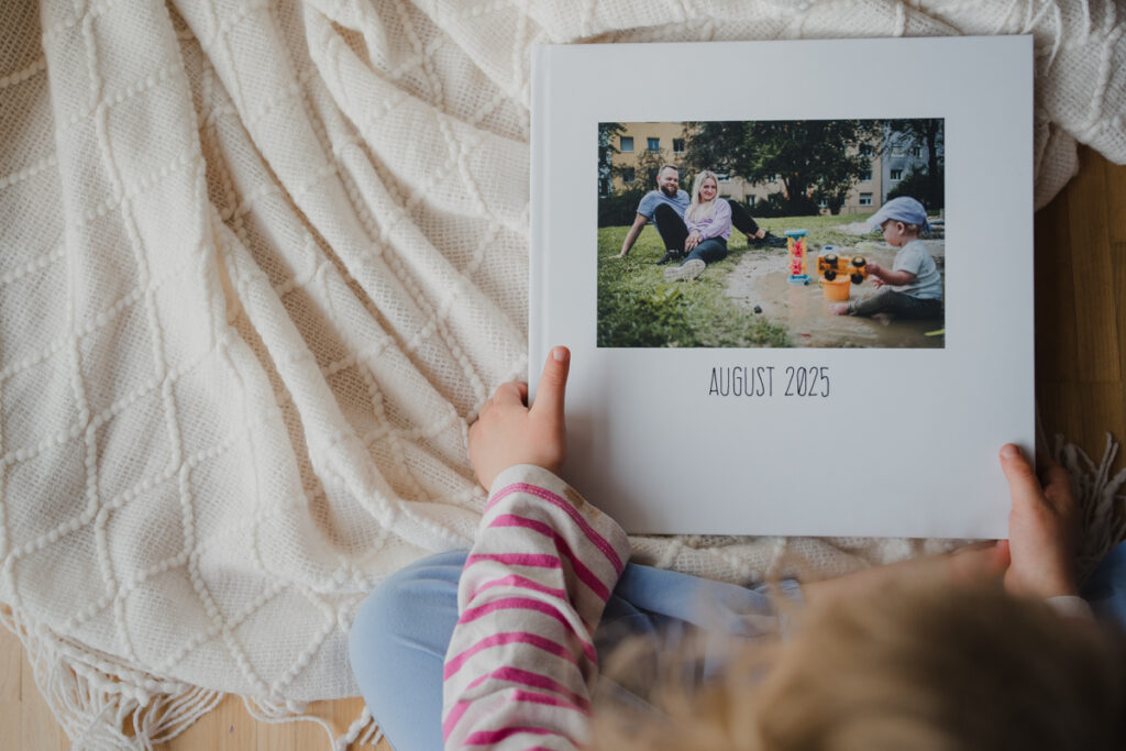 Kind blättert neugierig durch ein Familienfotobuch mit dokumentarischer Familienfotografie aus Graz