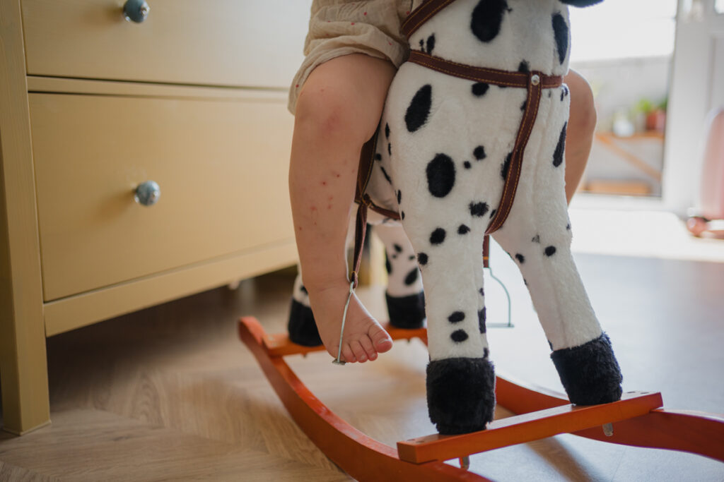 Detailaufnahme der Beine eines Kindes auf einem Schaukelpferd – ungestellter Familienalltag, dokumentarisch fotografiert in Graz