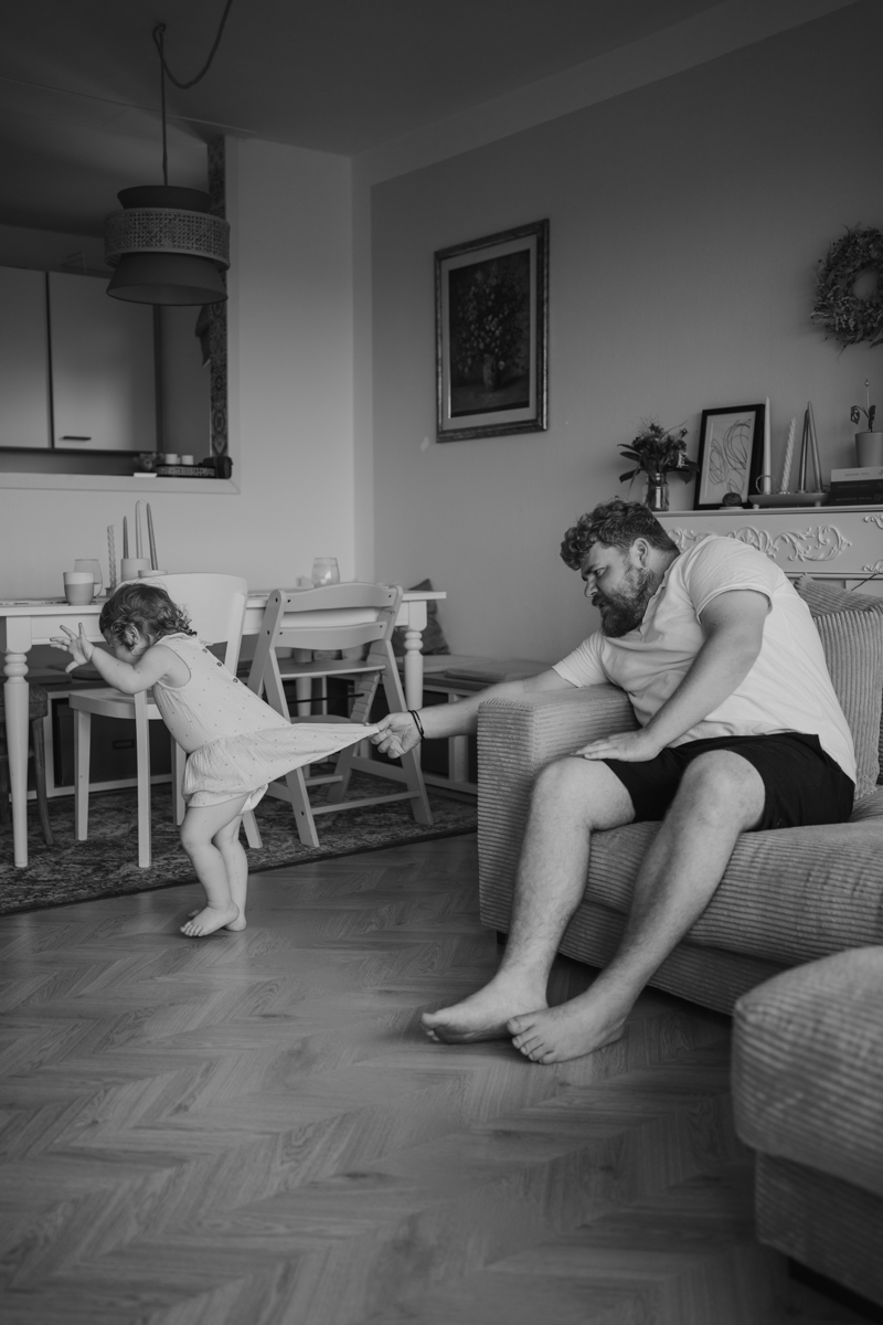 Ungestellter Moment zwischen Vater und Kleinkind, festgehalten am Rockzipfel – dokumentarische Familienfotografie in Graz und Umgebung