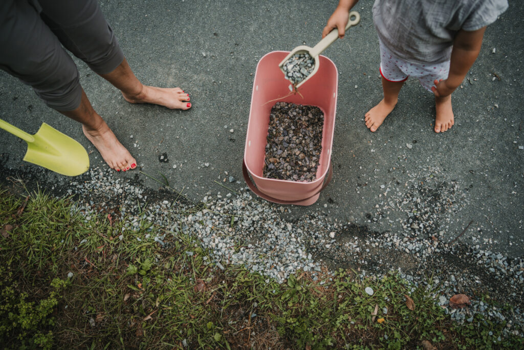 Oberansicht eines Kindes, das Kies schaufelt – authentischer Familienalltag, dokumentarisch fotografiert in Graz und Umgebung