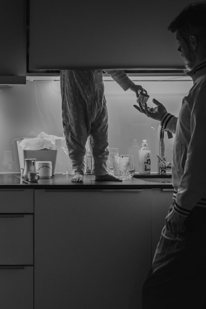 Ungestellter Moment, in dem ein Kind seinem Vater eine Tasse reicht – dokumentarische Familienfotografie in Graz und Umgebung