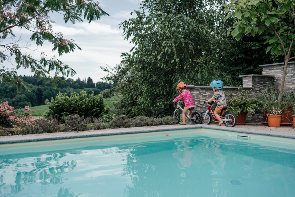 Zwei Kleinkinder fahren mit Laufrädern im Garten – authentischer Familienalltag in Graz und Umgebung