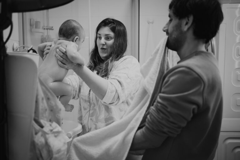 Mama holt Baby aus der Badewanne, Papa hält ein Handtuch bereit – authentischer Familienmoment in Graz und Umgebung