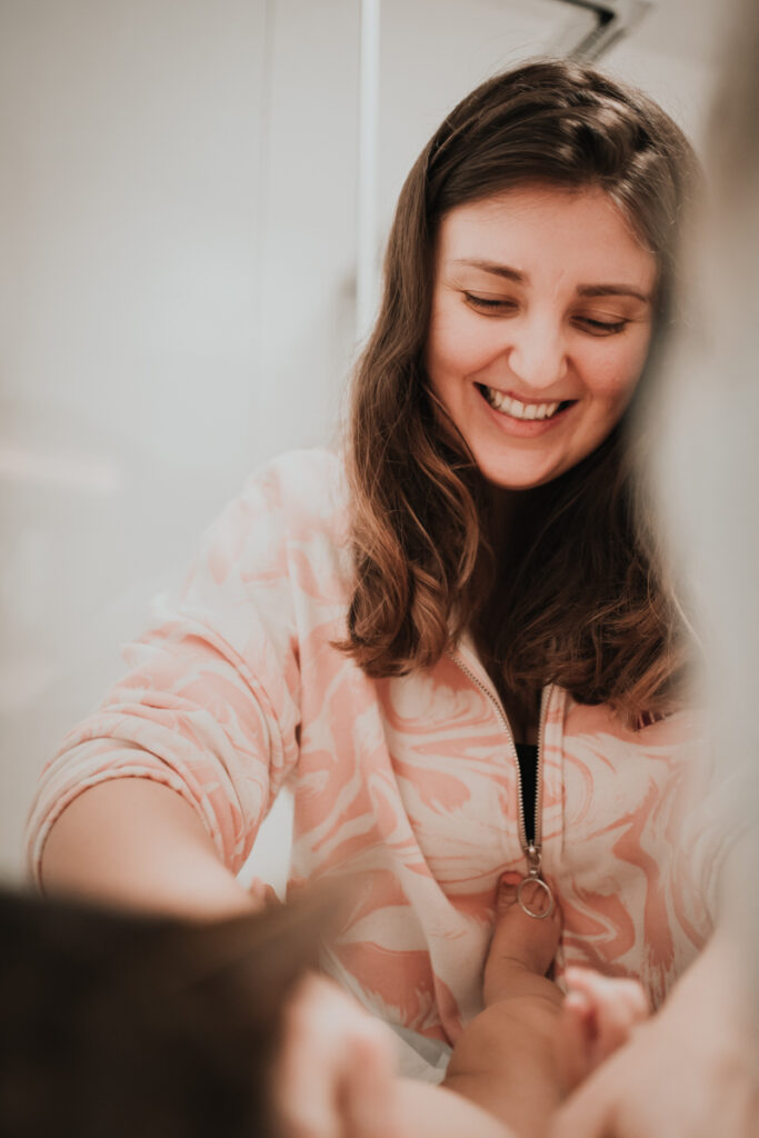 Lachende Mama wickelt ihr Baby – authentischer Familienalltag in Graz und Umgebung