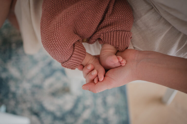 Detailaufnahme einer Mutter, die die Füße ihres Babys hält – dokumentarische Familienfotografie in Graz und Umgebung