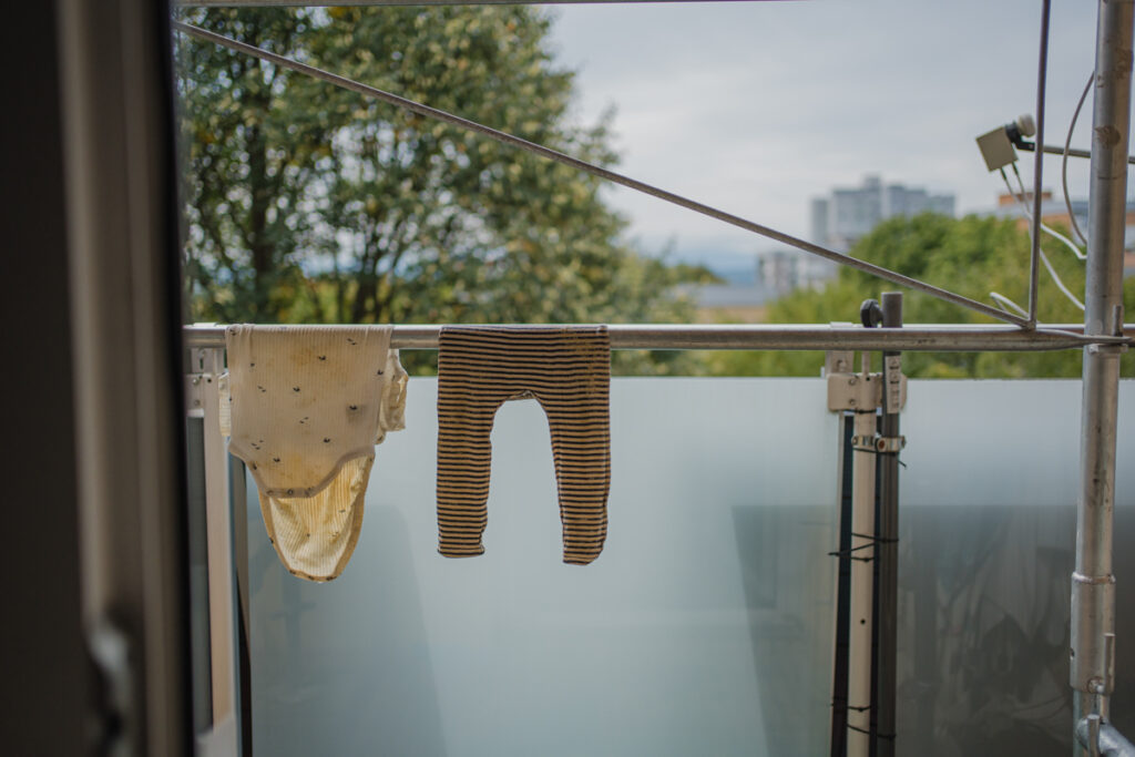 Ungestelltes Detail von dreckigem Babygewand am Balkon beim Trocknen – dokumentarische Familienfotografie in Graz und Umgebung