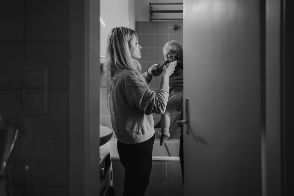 Badezimmeraufnahme: Mutter bereitet ihr Kind auf das Baden vor – liebevoller Familienalltag, dokumentarische Familienfotografie in Graz und Umgebung