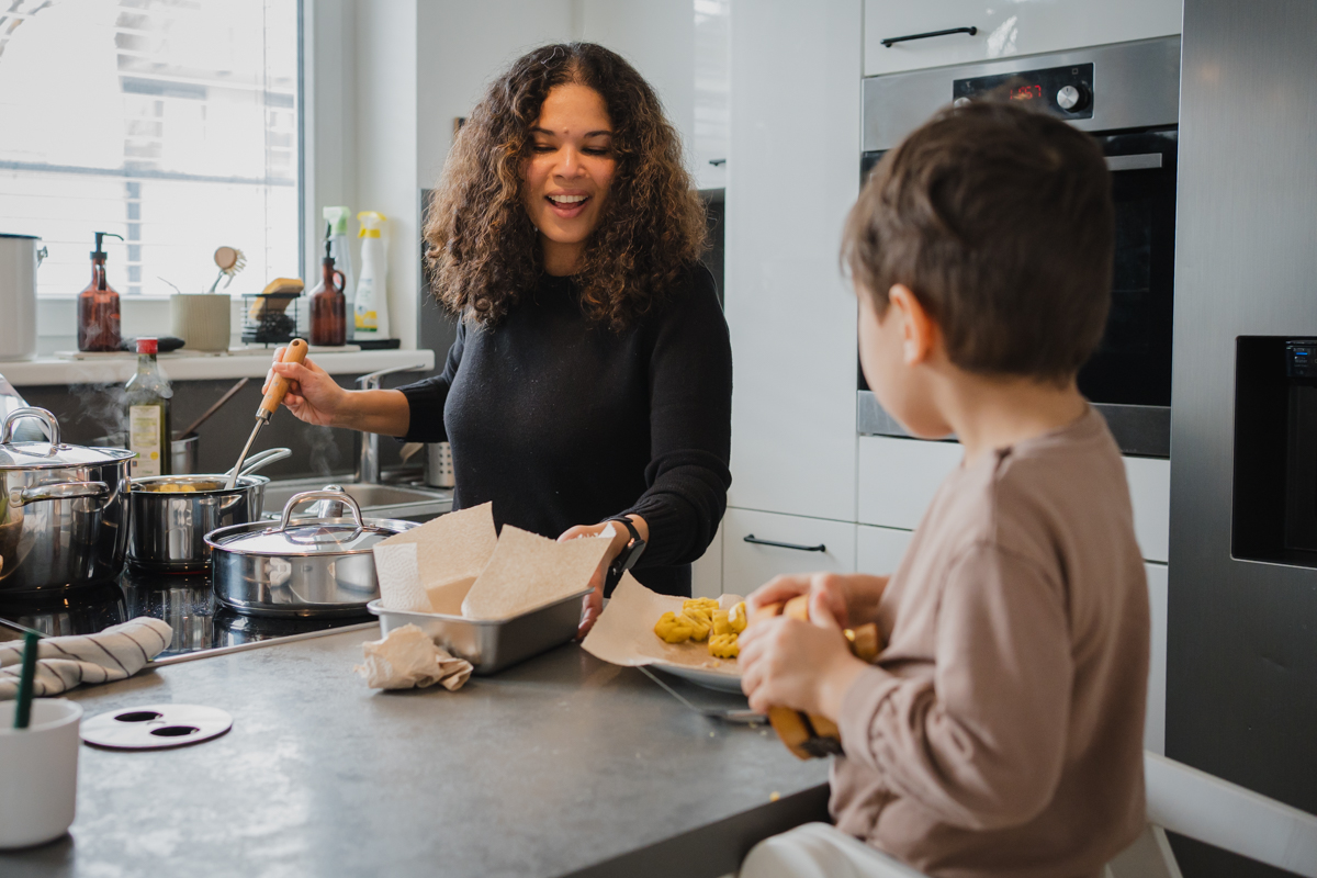 Mama steht gemeinsam mit ihrem Kleinkind in der Küche und sie kochen gemeinsam. Natürliche Familienfotografie in Graz und Umgebung.