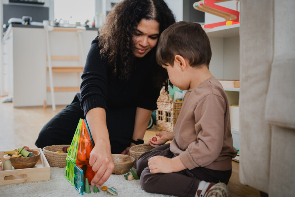 Mama sitzt mit Kleinkind am Boden und spielt gemeinsam. Echte Momente fotografisch festgehalten in Graz und Umgebung.