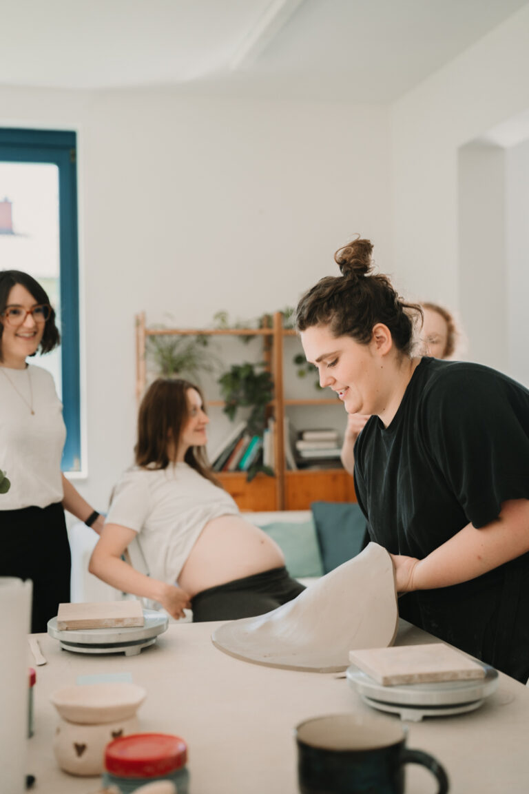 Eine Grazer Fotografin die Personal Brand Fotos anbietet begleitet eine Keramikerin aus Graz, wie sie eine Baby Belly Bowl mit einer Schwangeren Mama und deren Freundinnen anfertigt.