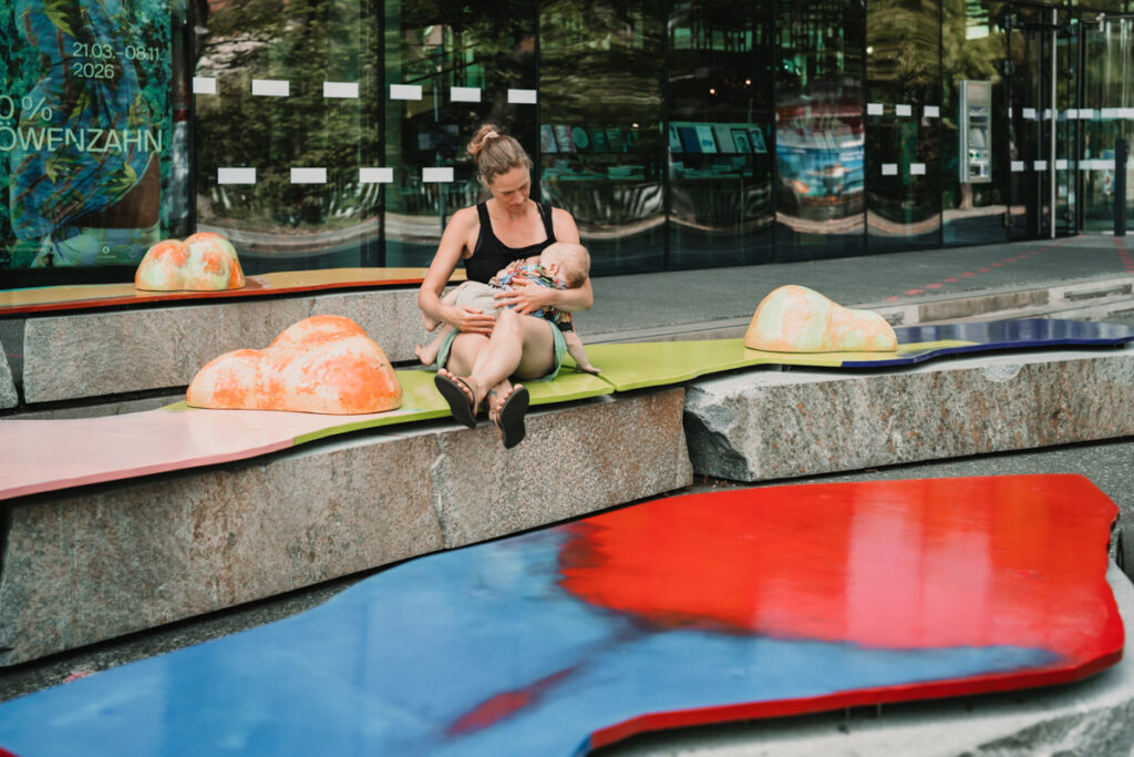 Familienfotografin Graz hat stillende Mama auf der Murinsel vor dem Kunsthaus Graz im Rahmen der Kampagne #ichstillwoichwill fotografiert